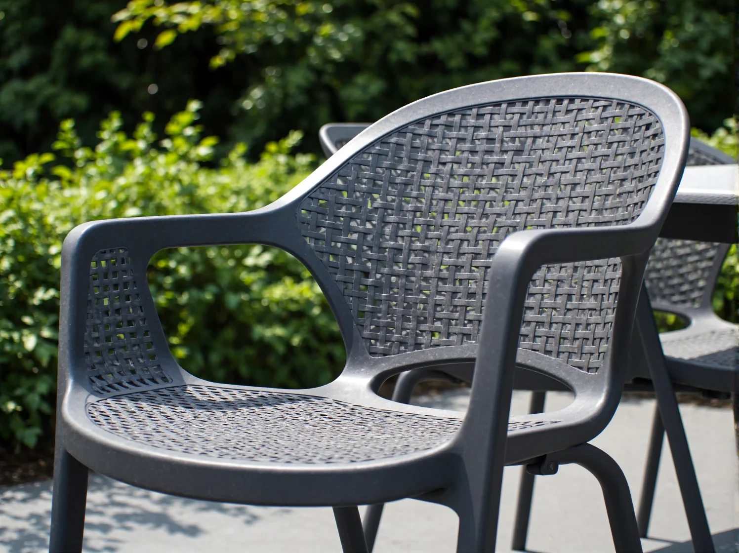 Białe krzesła ogrodowe z tworzywa sztucznego przy stole na zielonym trawniku.